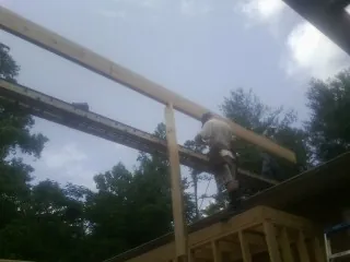 Carpenter setting a ridge beam over a new addition frame — Ice Dam Removal by Roofing Brothers in Westcliffe