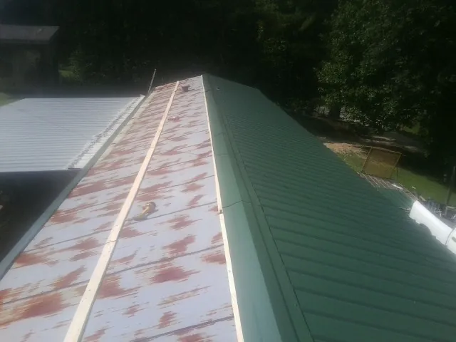 Old rusted panels beside newly installed green metal roofing — Wind Damage Roof Repair by Roofing Brothers in Westcliffe