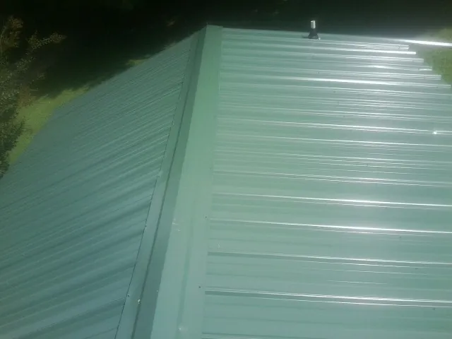New green metal panels meeting at the ridge of a roof — Flat Roof Repair work by our crew in Westcliffe