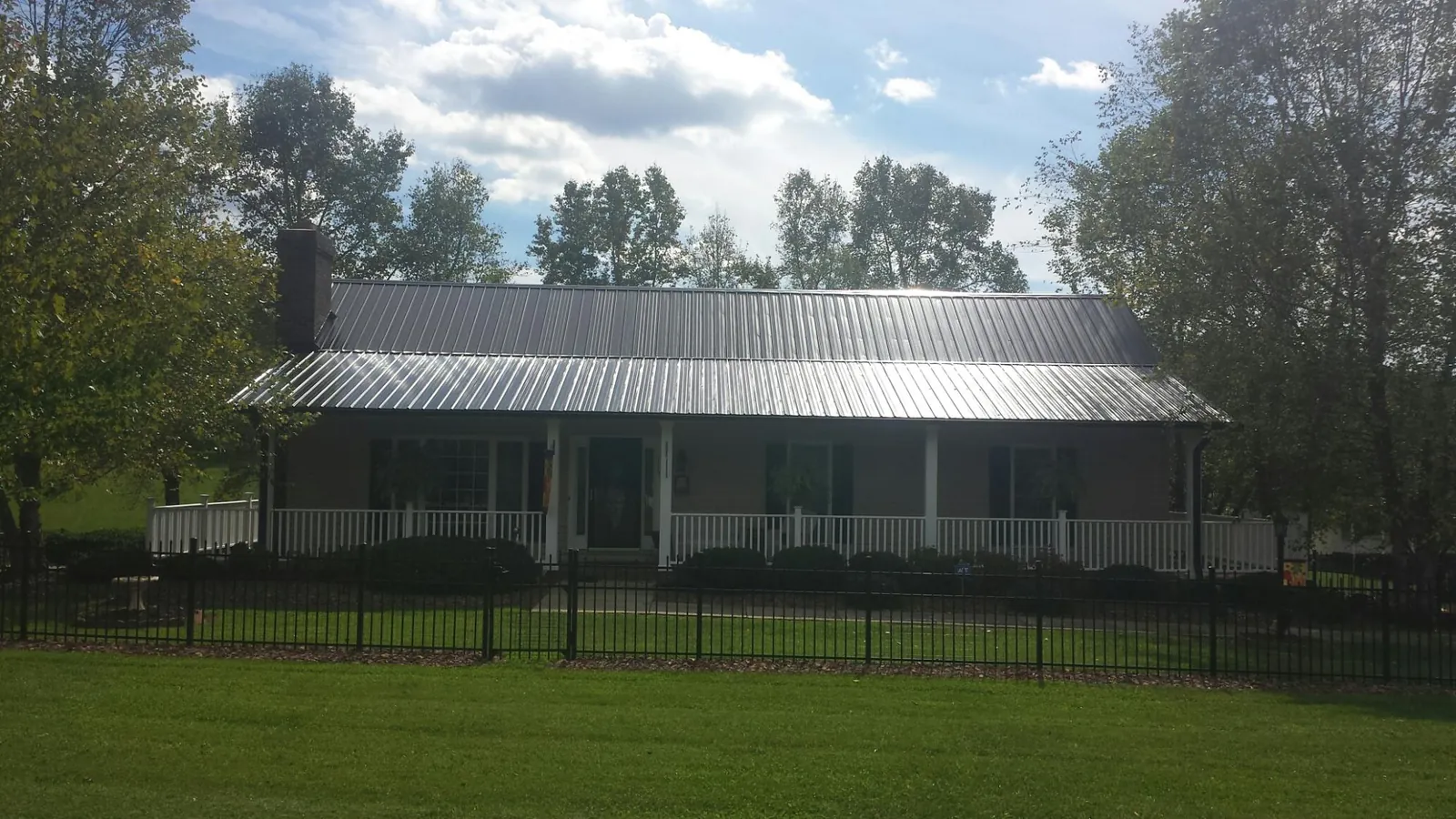 Gray metal roof on a brick ranch with a full width front porch — Gutter Guard Installation work by our crew in Westcliffe
