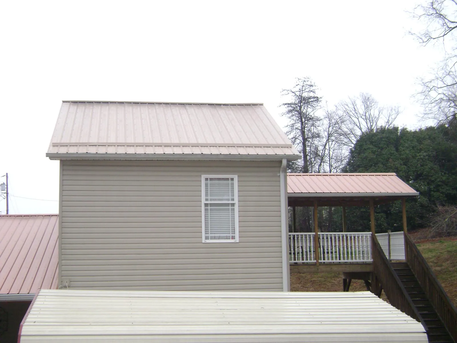 Tan metal roofs on a two story addition and attached porch, from a Roof Replacement job in Westcliffe
