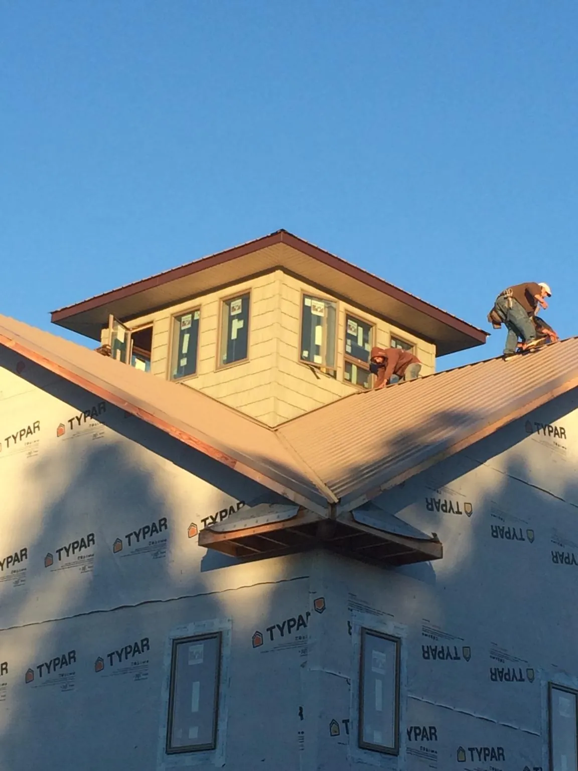 Roofers working around a rooftop cupola on a new metal roof at sunset — Roof Waterproofing in Westcliffe by Roofing Brothers